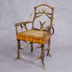 a chair made out of branches with a wooden seat and back rest, sitting on a gray background