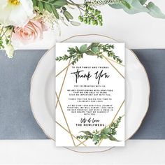 a table setting with flowers and greenery on it, including an elegant menu card