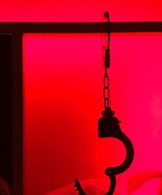 a red light is shining on a bed with a black hook hanging from it's side