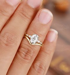 a woman's hand with a diamond ring on top of her finger and an engagement band