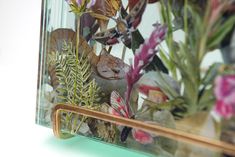 a glass vase filled with flowers and plants