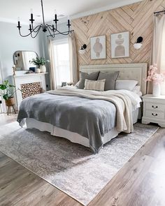 a bedroom with wood paneled walls and gray bedding, white dressers, and chandelier