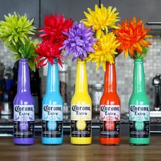 four bottles with flowers in them sitting on a counter