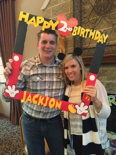 a man and woman holding up mickey mouse signs