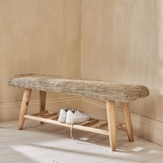 a pair of white shoes sitting on top of a wooden bench next to a wall