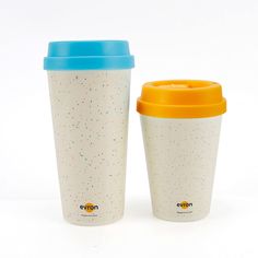 two coffee cups sitting next to each other on a white surface with colorful sprinkles