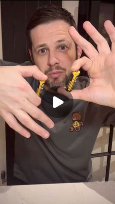 a man holding up two yellow and black toothbrushes in front of his face