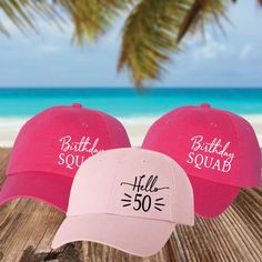 two pink hats sitting on top of a wooden table next to the ocean and beach