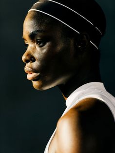 a woman in white shirt and headband with dark background