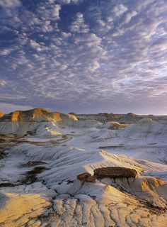 the landscape is covered in white sand and blue sky with wispy clouds above