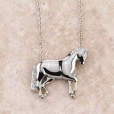 a silver and black horse necklace on a white marble surface with a chain attached to it