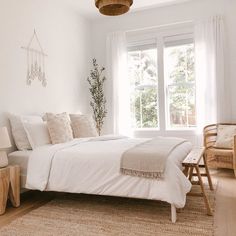 a bedroom with white walls and natural wood furniture, including a bed in the center