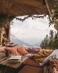 a wooden table with pillows and blankets on it in the middle of a balcony area