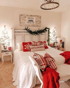 a bedroom decorated for christmas with white bedding and red pillows