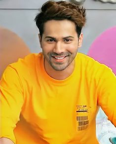 a man in an orange shirt smiles at the camera