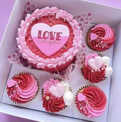 cupcakes with pink frosting and red icing in a box