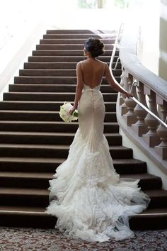 a woman in a wedding dress walking down some stairs