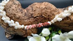 a close up of a necklace on a rock near flowers