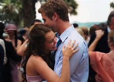 a man and woman embracing each other in front of a crowd