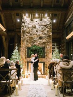 a bride and groom standing at the end of their wedding ceremony in front of a stone fireplace