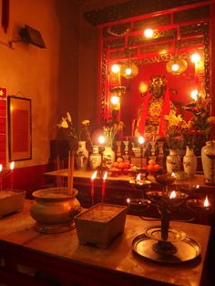 candles are lit in front of a shrine with buddha statues and other items on the table