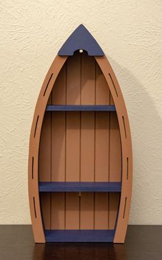 a wooden shelf with a boat shaped bookcase on it's side, sitting on a table