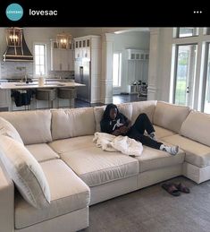 a man laying on top of a couch in a living room next to a kitchen