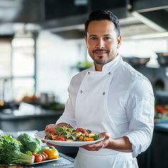 a man holding a plate of food in a kitchen with vegetables on the counter top