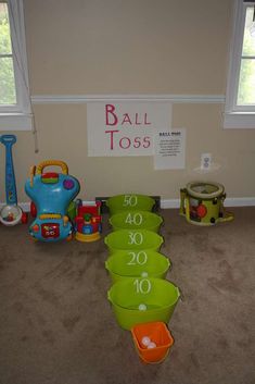 toys are lined up on the floor in front of a ball toss sign