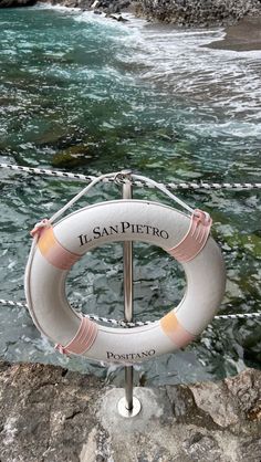 a life preserver sitting on top of a rock next to the ocean