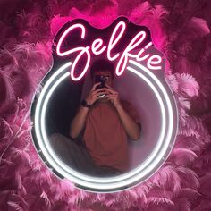 a man taking a selfie in front of a mirror with pink feathers around it