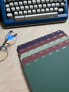 an old typewriter sitting on top of a wooden table next to a pair of glasses