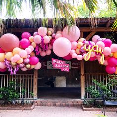 the entrance to a restaurant decorated with pink, yellow and purple balloons that spell out congratulations