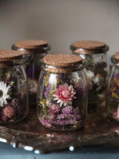 several glass jars filled with flowers on top of a table