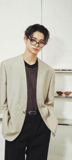 a young man wearing glasses standing in front of a shelf with sunglasses on his head