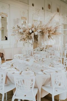 the tables are set with white chairs and centerpieces