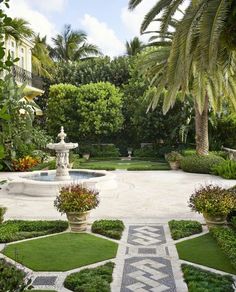 the garden is surrounded by lush green trees and plants, with a fountain in the center