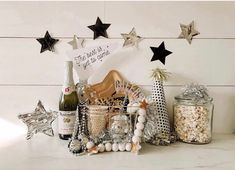 a table topped with bottles of wine and other holiday decorations next to stars on the wall