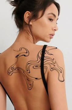 the back of a woman's body with an abstract tattoo design on her shoulder