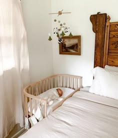 a crib with a baby in it next to a window and pictures on the wall