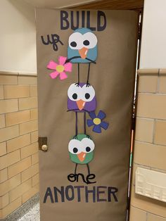 a door decorated with owls and flowers in the shape of words build up, one another