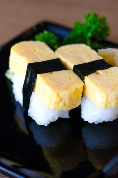 four pieces of sushi sitting on top of a black plate