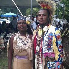 two people standing next to each other in native clothing