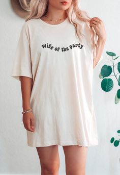 a woman wearing a white t - shirt with the words wife of the party printed on it