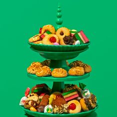 three tiered trays filled with different types of pastries and cookies on green background