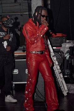 a man in red leather outfit standing next to a microphone