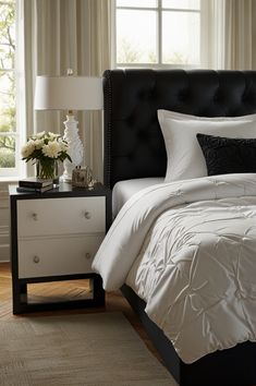 a bed with white and black comforters in a bedroom next to a window,