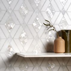 two vases are sitting on a shelf in front of a wall with geometric tiles