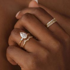 a woman's hand with three different rings on her finger and one ring in the other