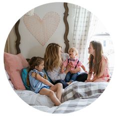 a group of women sitting on top of a bed with a baby in her lap